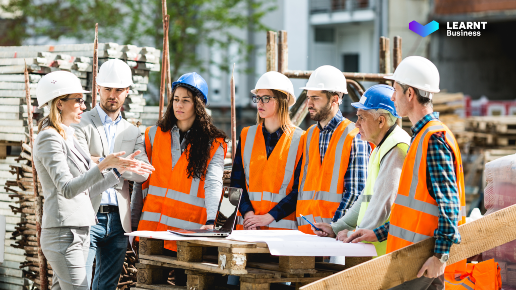 A construction manager training workers on-site using digital tools to improve workforce efficiency and compliance.