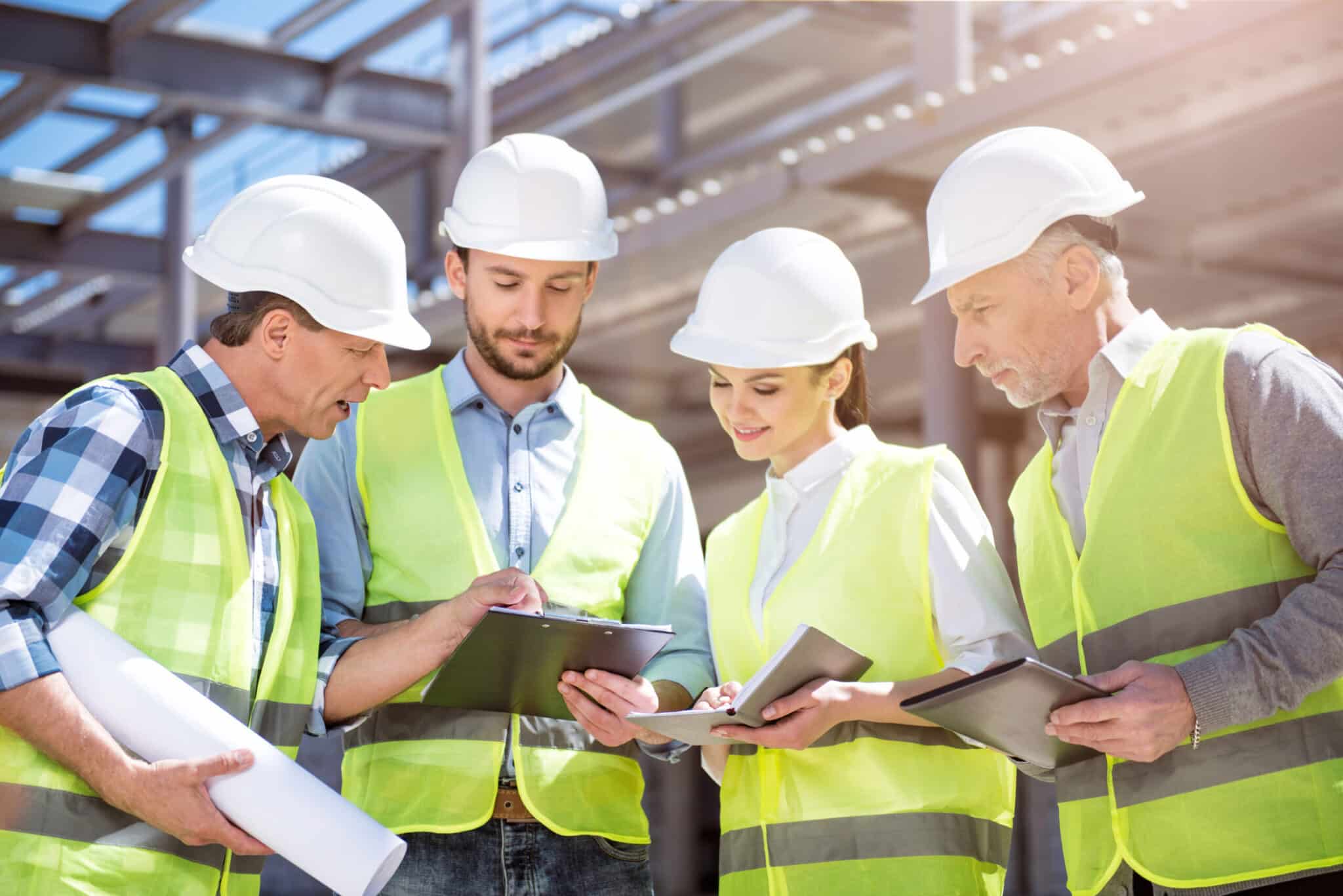 Construction workers in hard hats and high visibility vests reviewing training documents on a building site