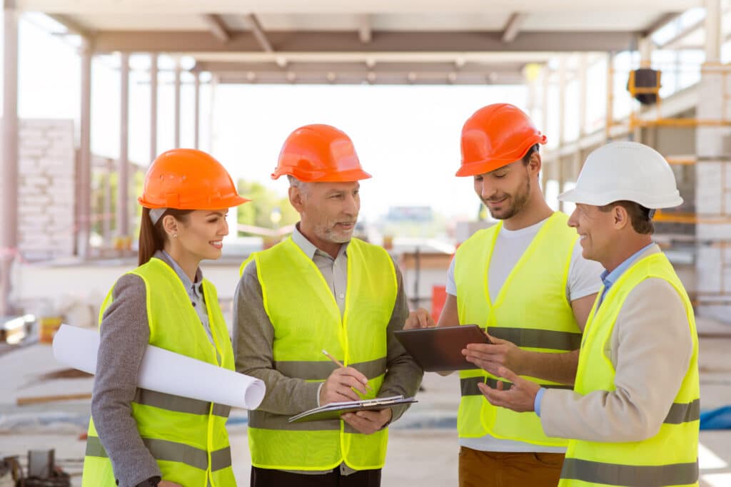 Construction workers reviewing site plans and safety training on a tablet, leveraging digital workforce training for compliance and productivity.