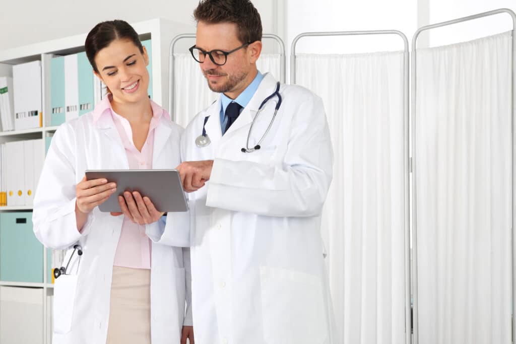 A senior doctor training a junior colleague using a digital learning platform.