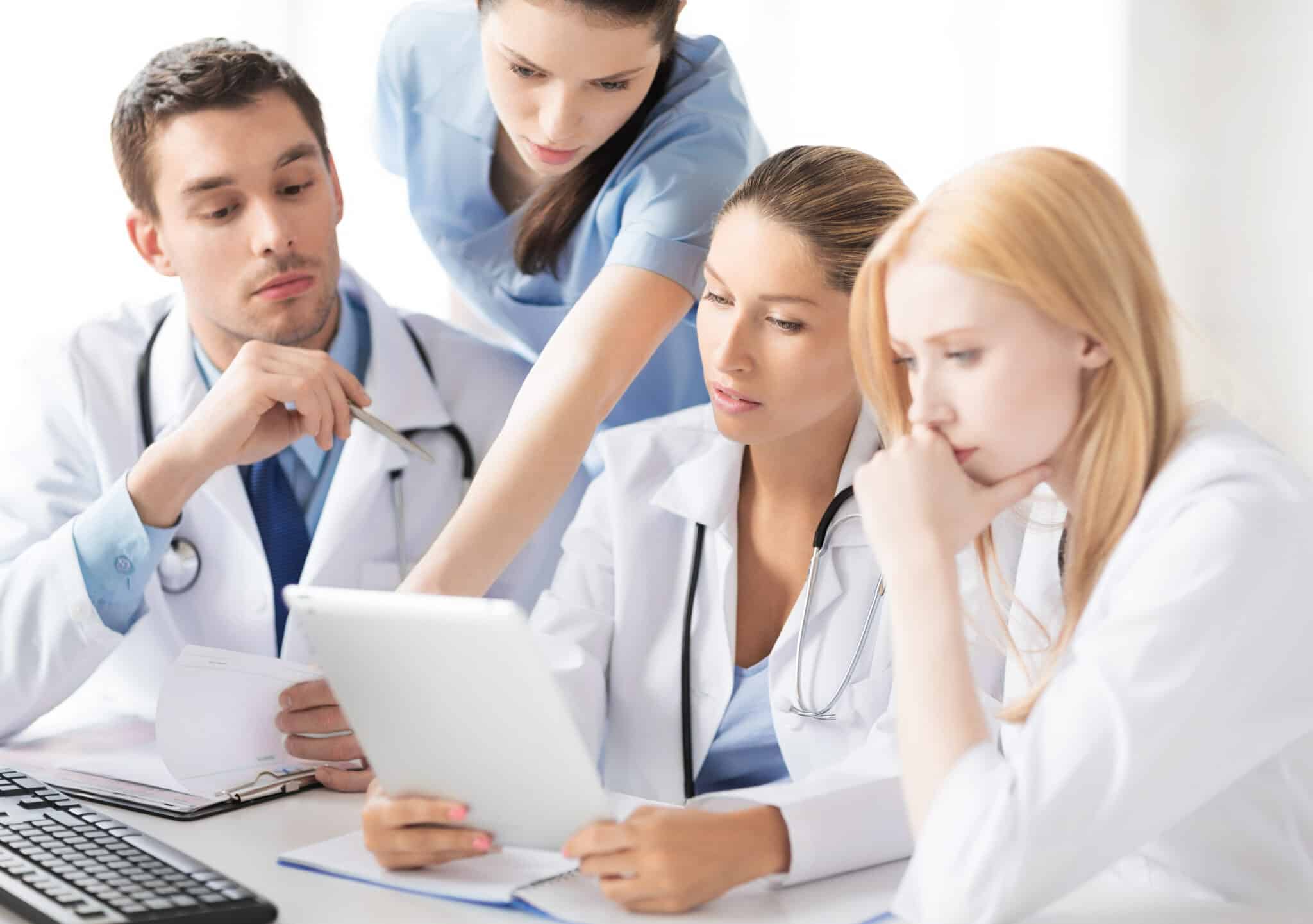 Healthcare professionals undergoing digital training on a tablet to enhance patient care and compliance.