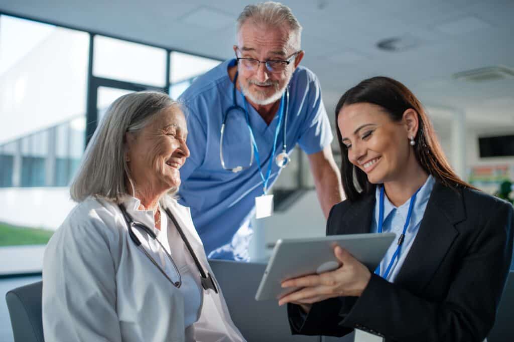 A healthcare team discussing training content on a tablet for efficient learning.